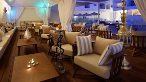 Een terras met houten meubels, comfortabele zittingen en een decoratieve shisha.