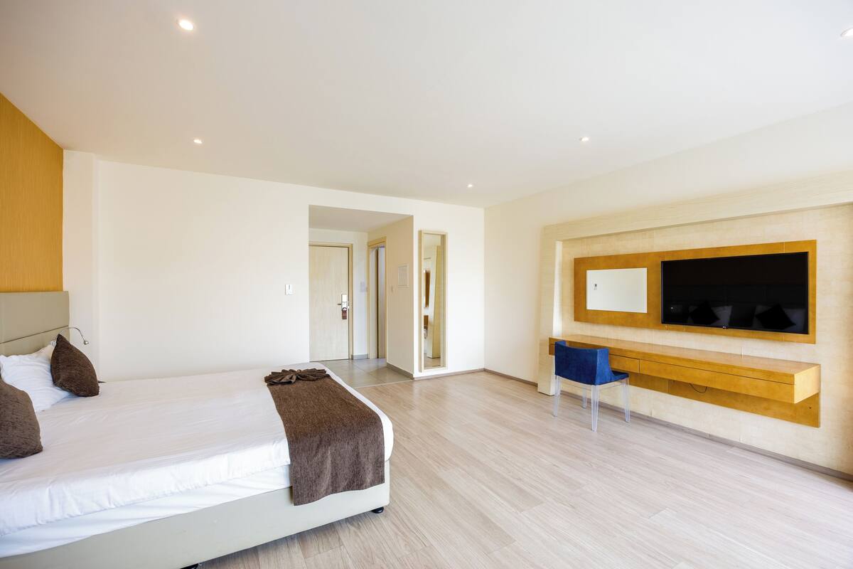Een moderne hotelkamer met een groot bed, een bureau en een aan de muur bevestigde televisie.