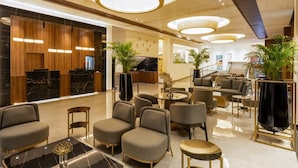 Een moderne lobby met een receptiebalie, een zithoek en een trap.