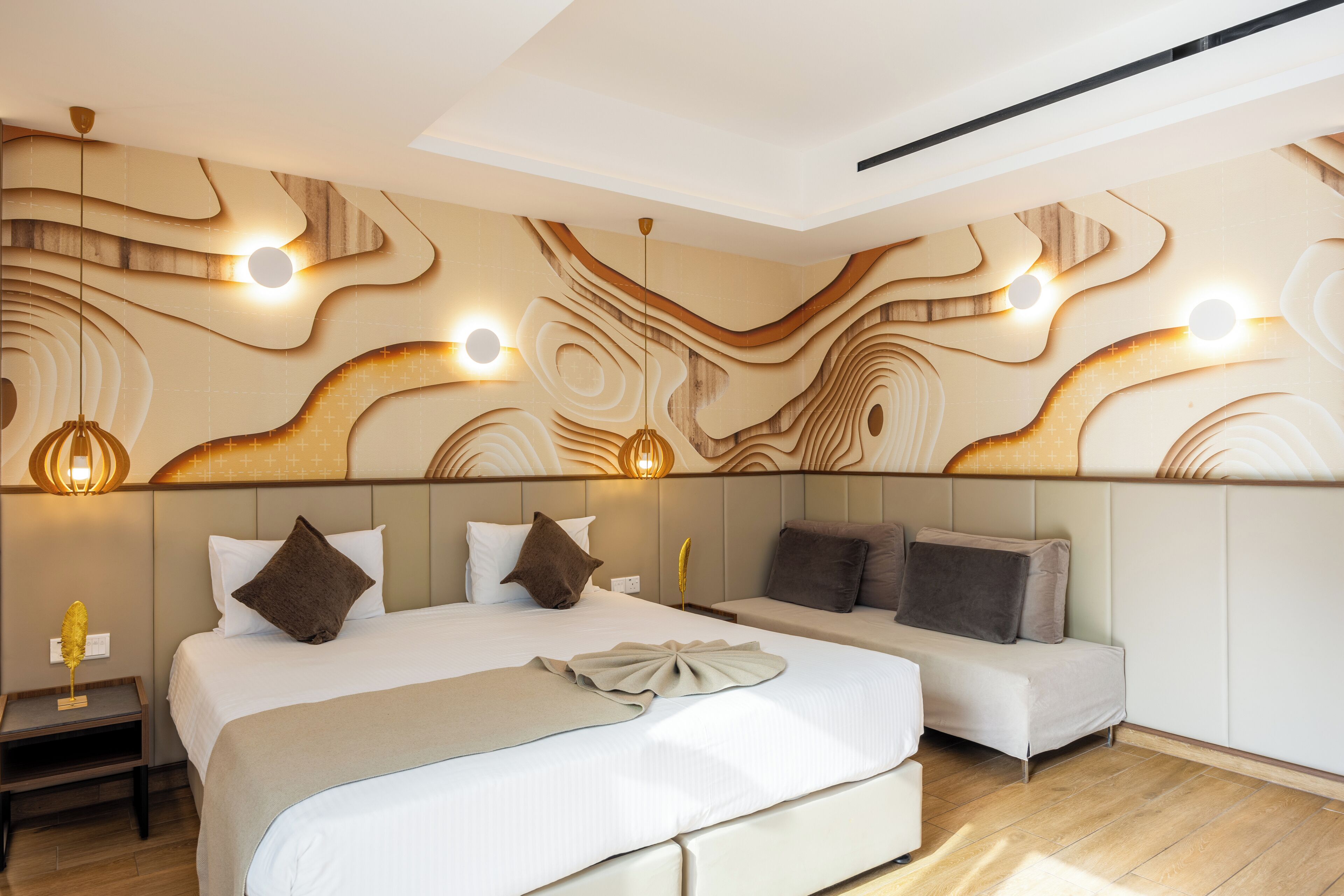 Une chambre d’hôtel moderne dotée d’un grand lit, d’un canapé et d’un décor mural original.