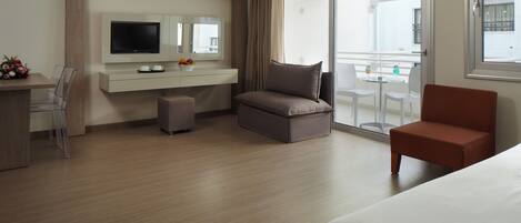 A hotel room with a bed, a TV, a desk, and a balcony with a table and chairs.