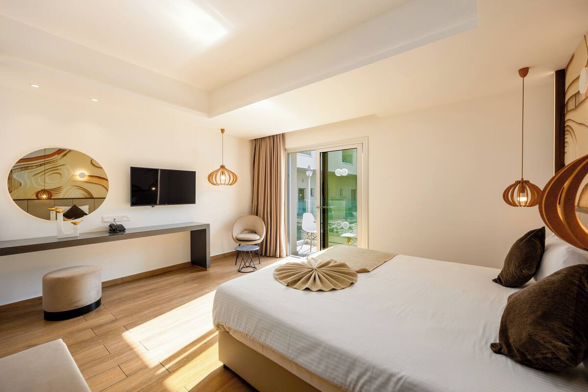Een moderne hotelkamer met een groot bed, een bureau, een televisie en een balkon met uitzicht.