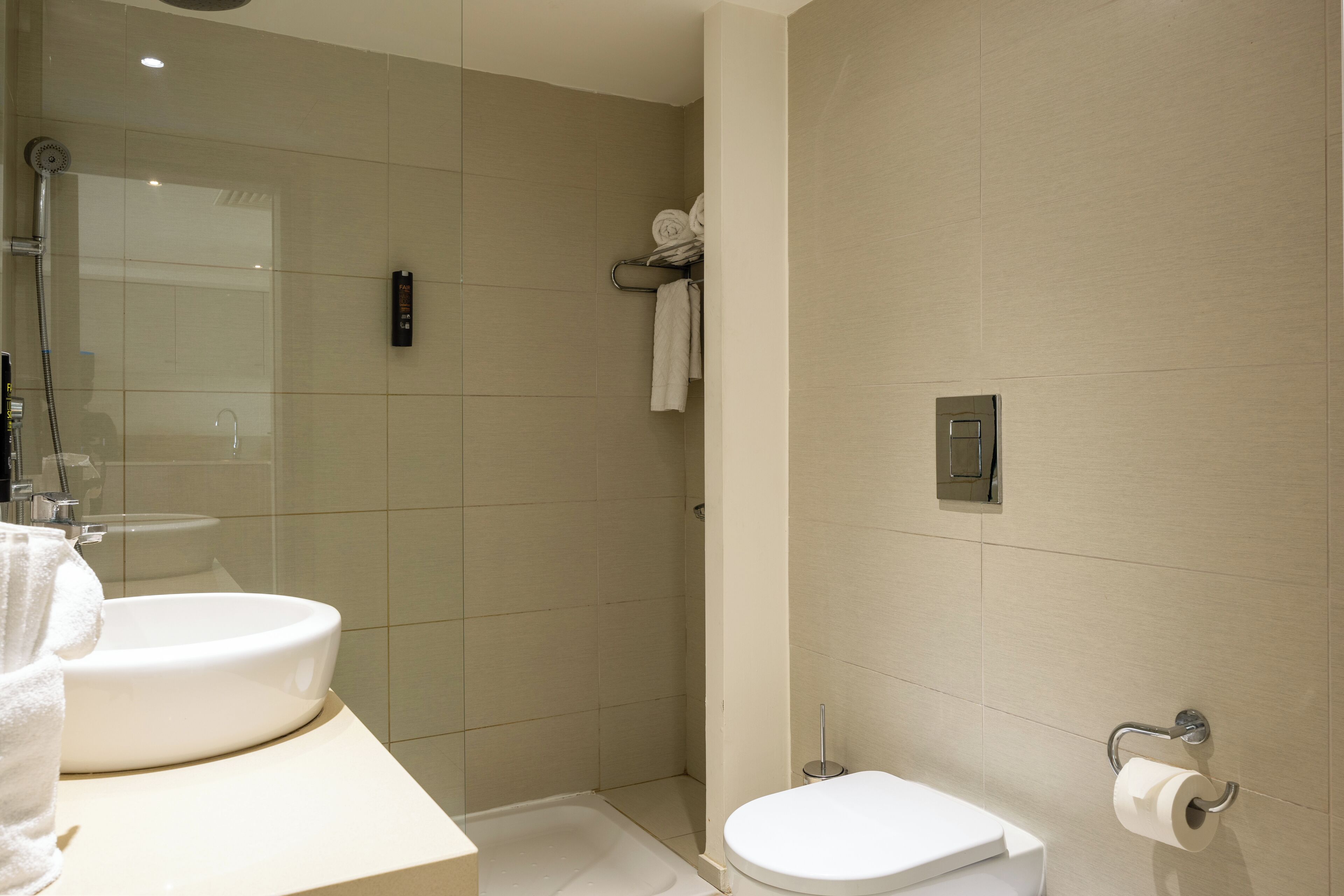 Un baño moderno con lavamanos, inodoro y ducha.