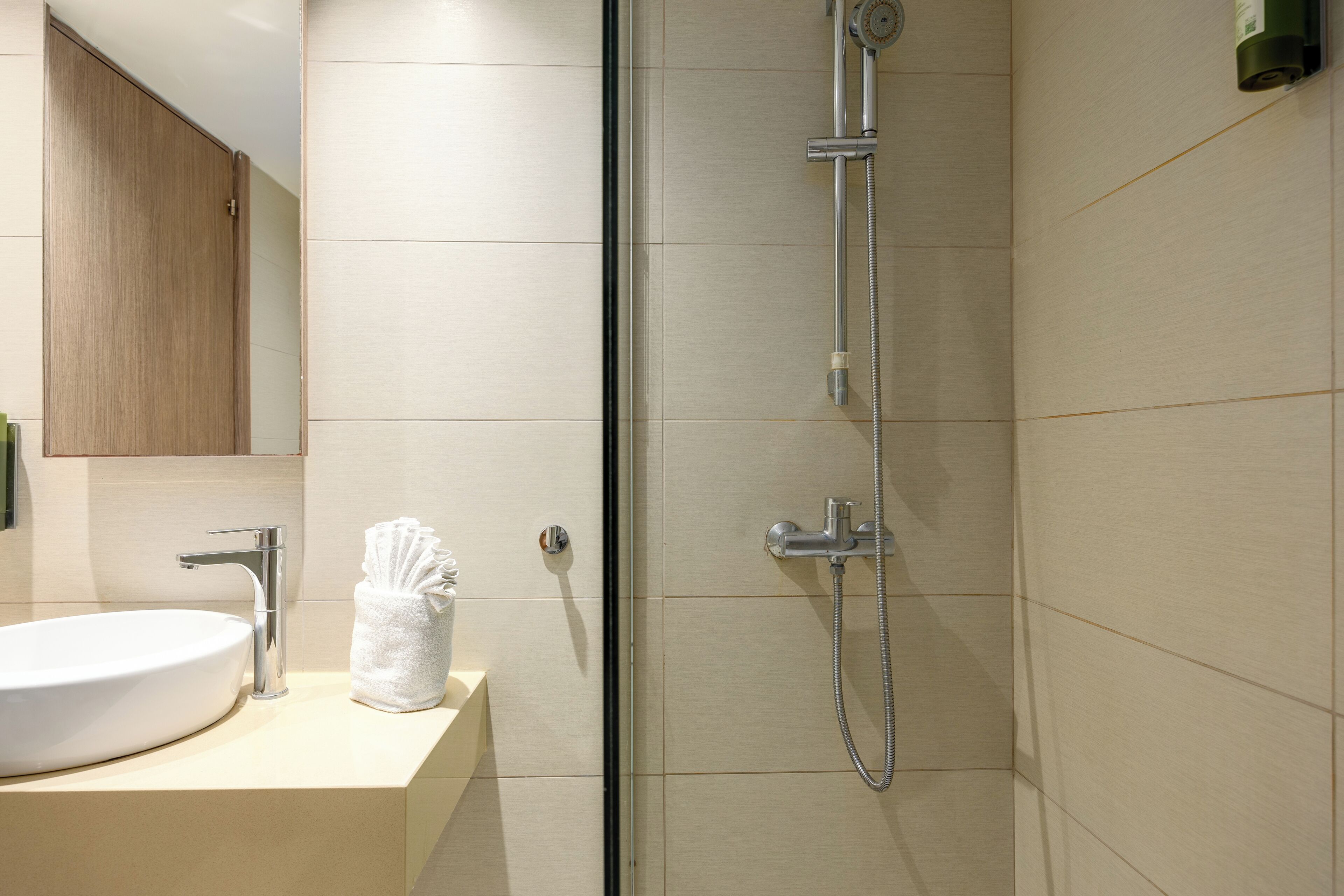 A bathroom with a sink, mirror, and shower.
