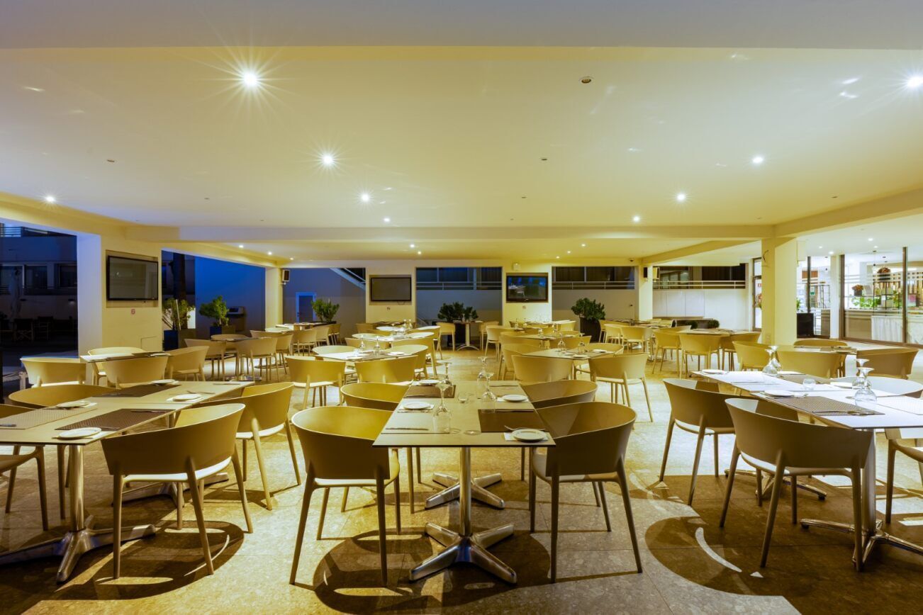 A spacious dining area with multiple tables and chairs, arranged in a modern layout.