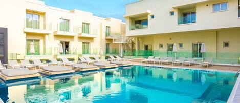 A swimming pool with lounge chairs and a building with balconies.