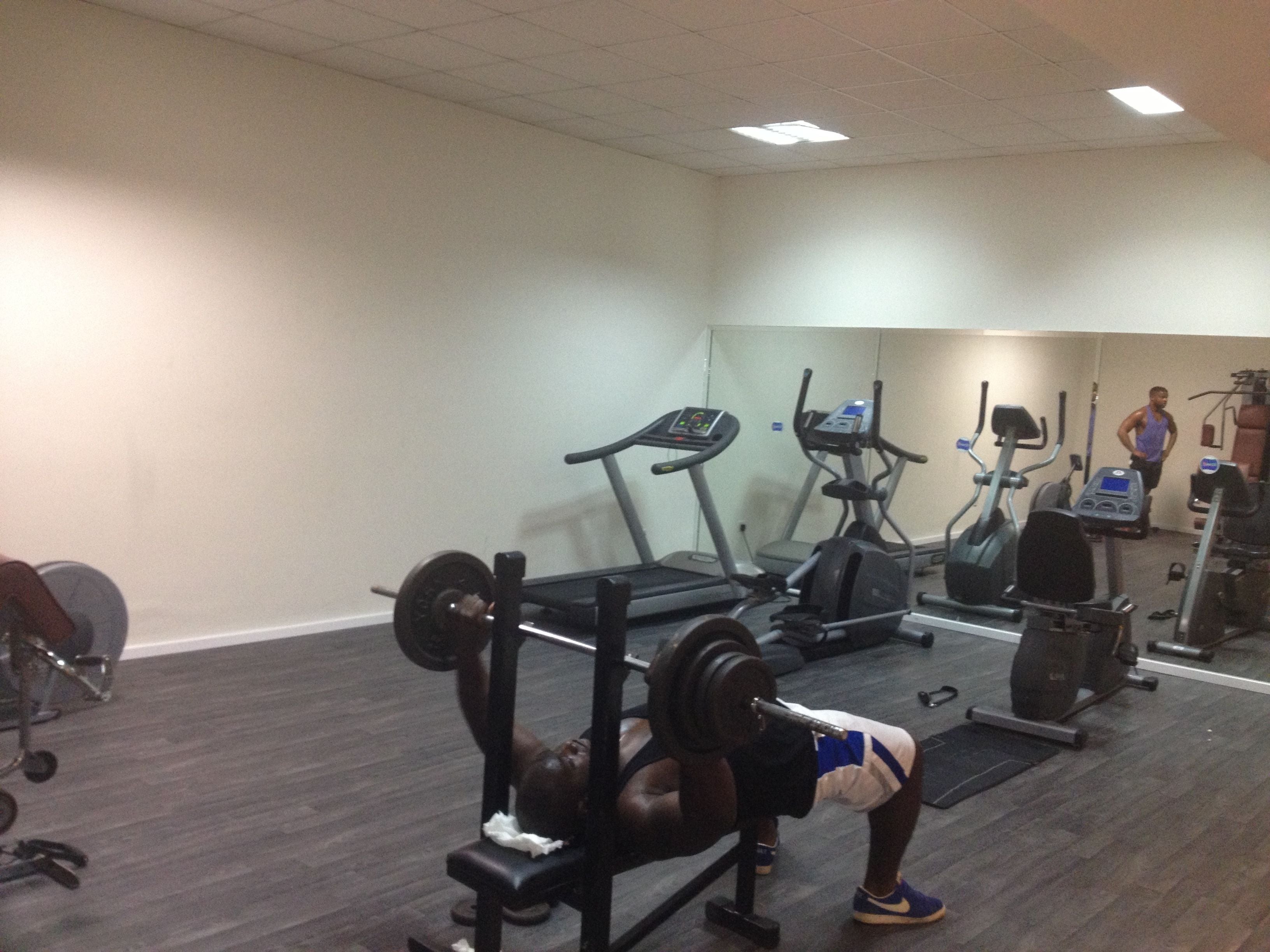 Un gimnasio con bancos de pesas, cintas de correr y equipo de ejercicio.