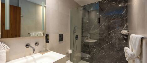 A modern bathroom with a glass-enclosed shower, a white sink, and a toilet.