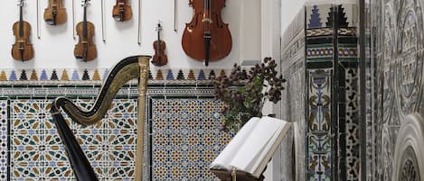 Una habitación con un arpa, un atril para violín y una mesa con un libro.