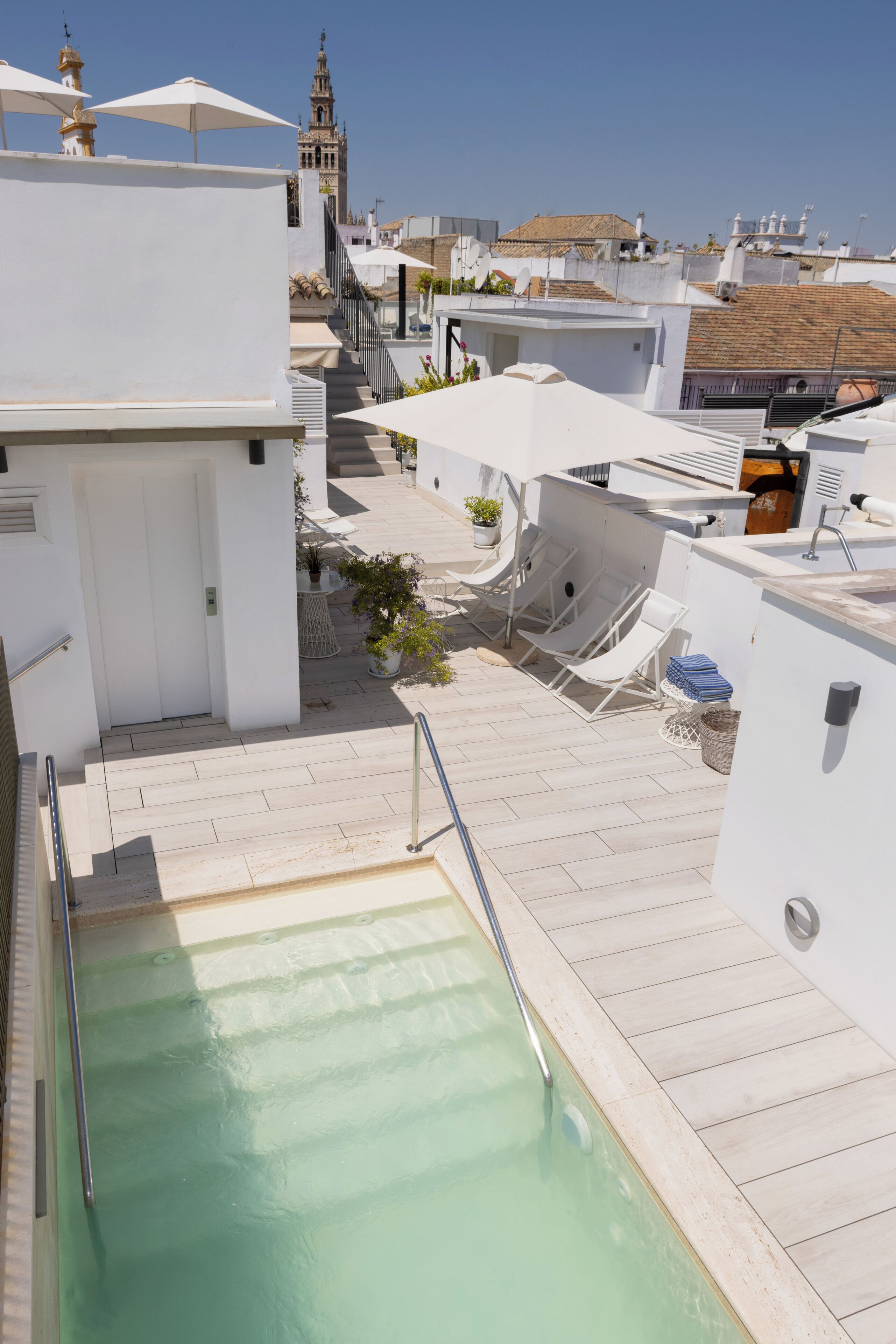 Un espace piscine aménagé sur le toit, offrant une vue dégagée sur une tour en arrière-plan.