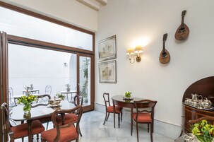 Un comedor con un ventanal amplio, sillas de madera, una mesa con un jarrón de flores e iluminación empotrada.