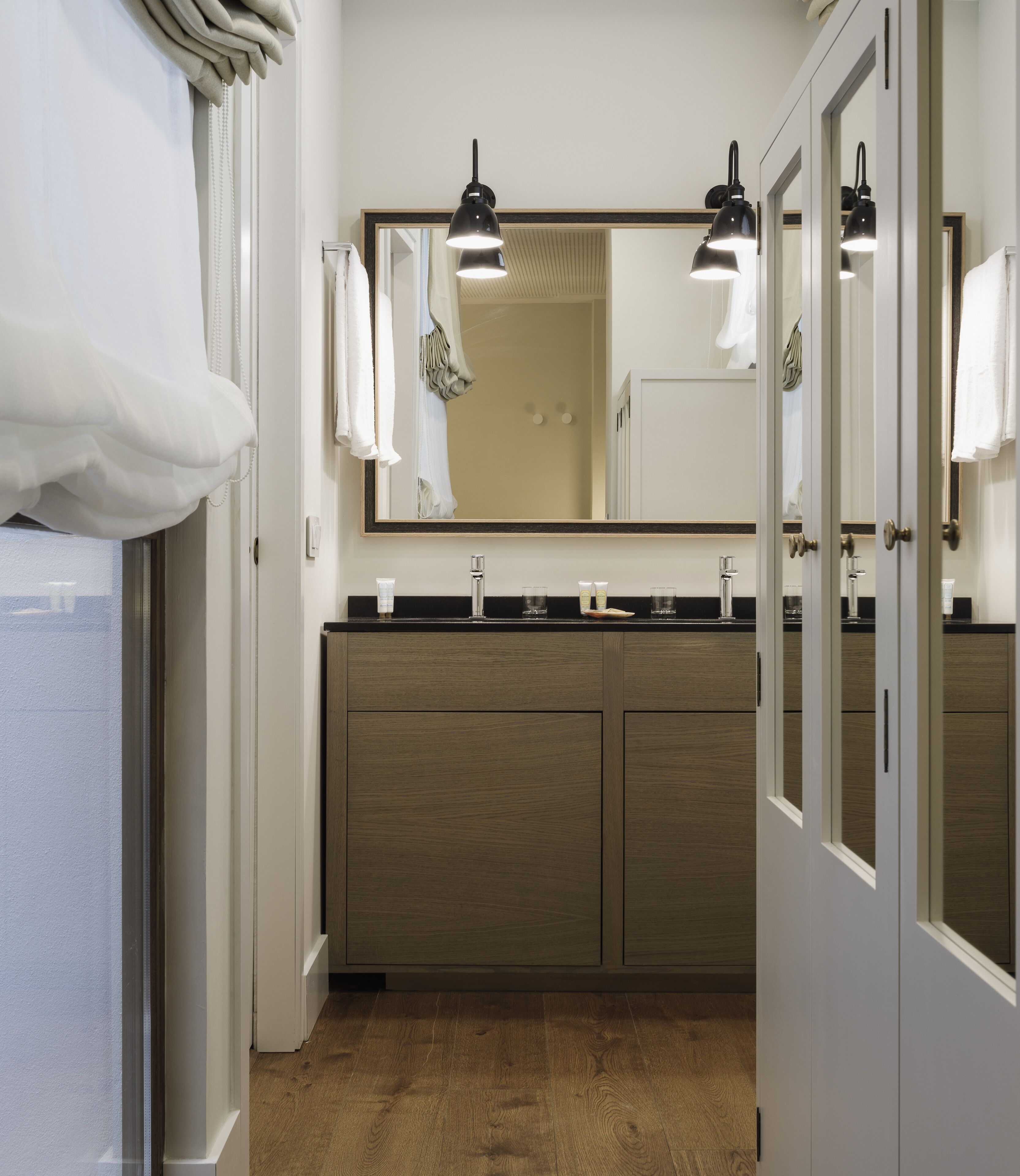 A bathroom with a wooden vanity, two sinks, and a large mirror.