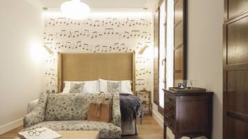 A bedroom with a patterned wall, a bed, a sofa, a small table, and a wardrobe.