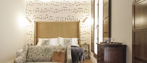 A bedroom with a patterned wall, a bed, a sofa, a small table, and a wardrobe.