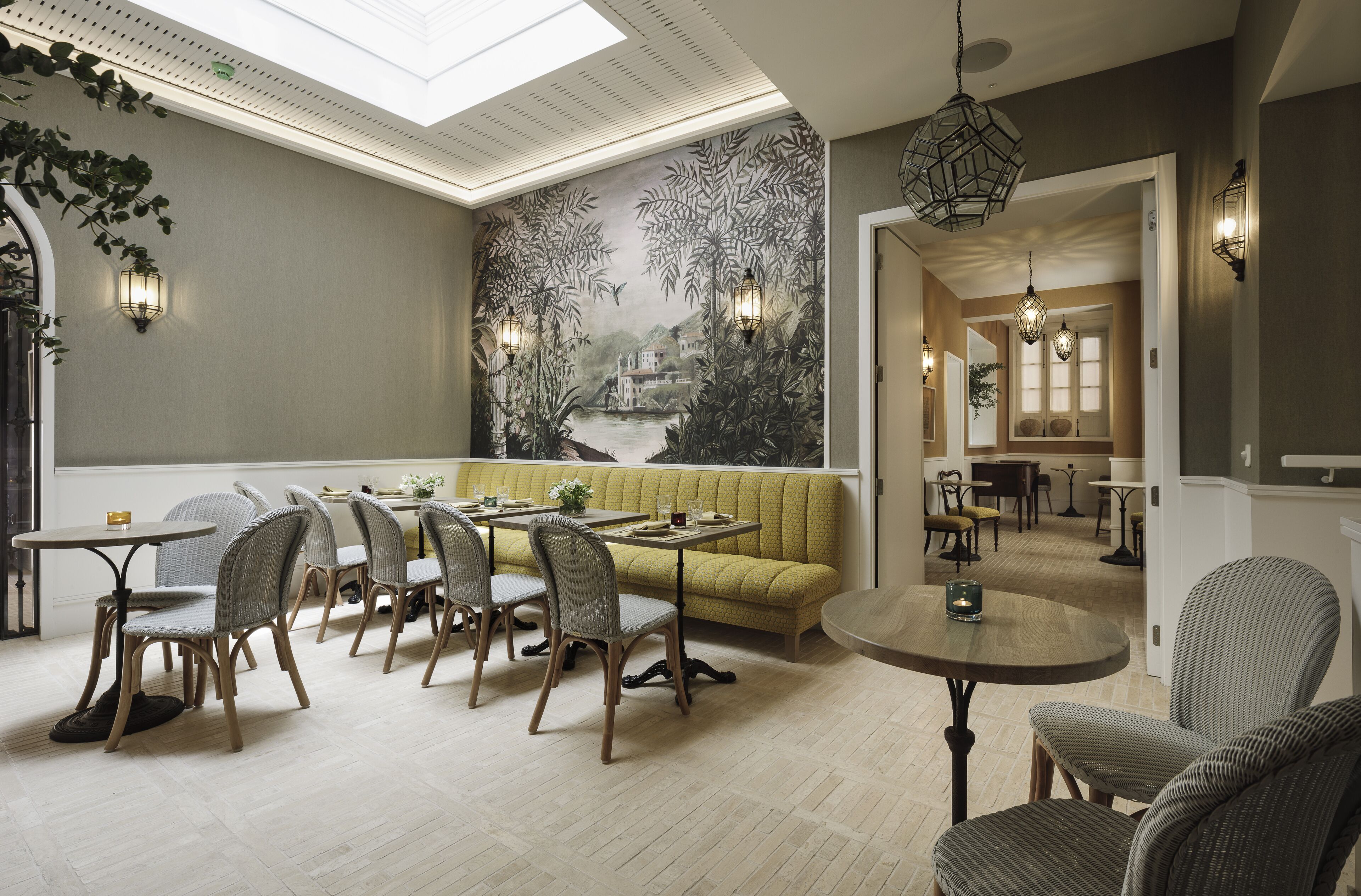A dining area with a high ceiling, a mural, and a view into another room.