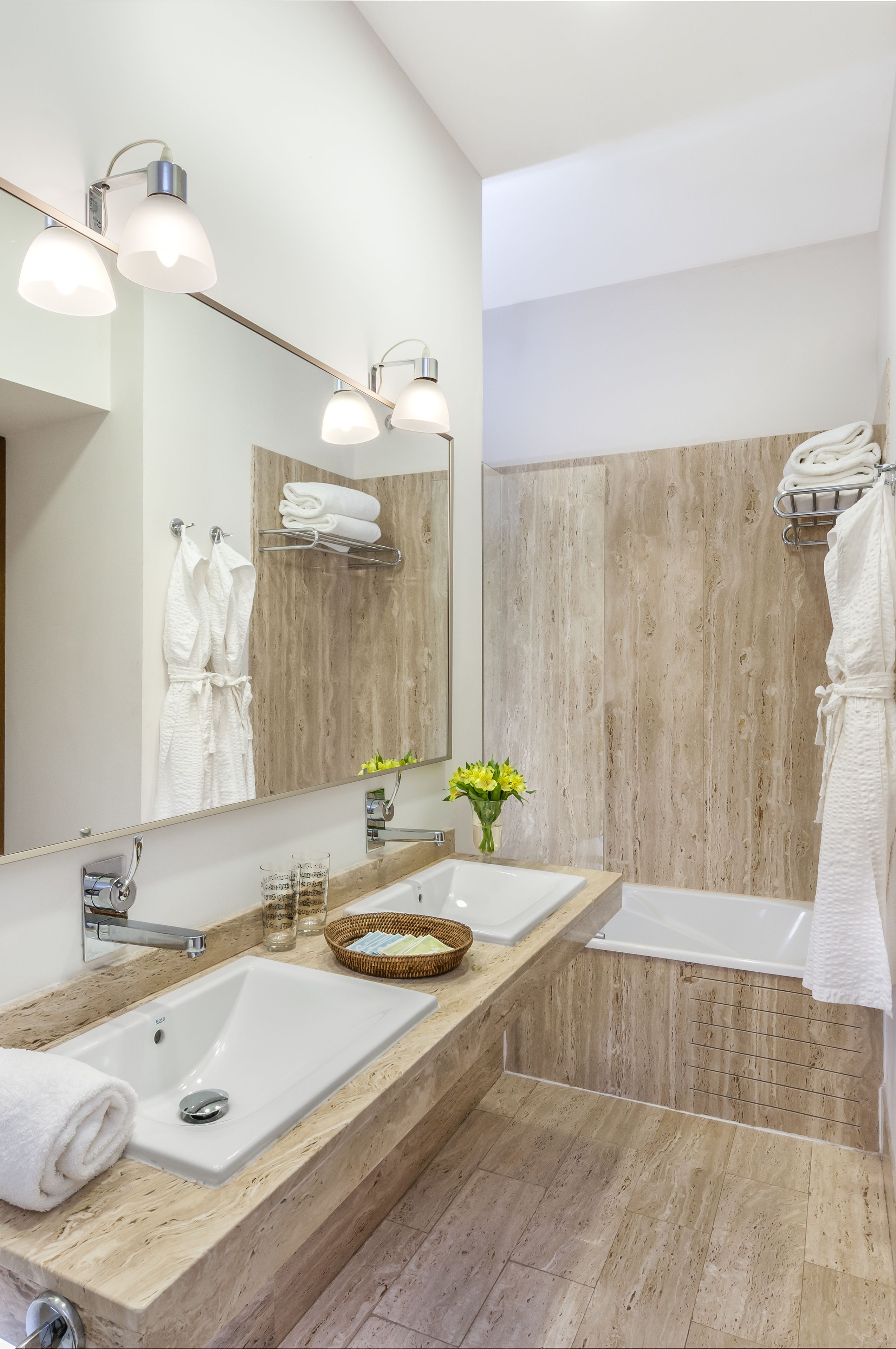 Un baño moderno con un espejo grande, dos lavamanos, una bañera y paneles de pared de madera.