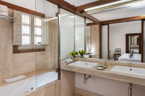 A modern bathroom with a glass shower enclosure, two sinks, and a large mirror.