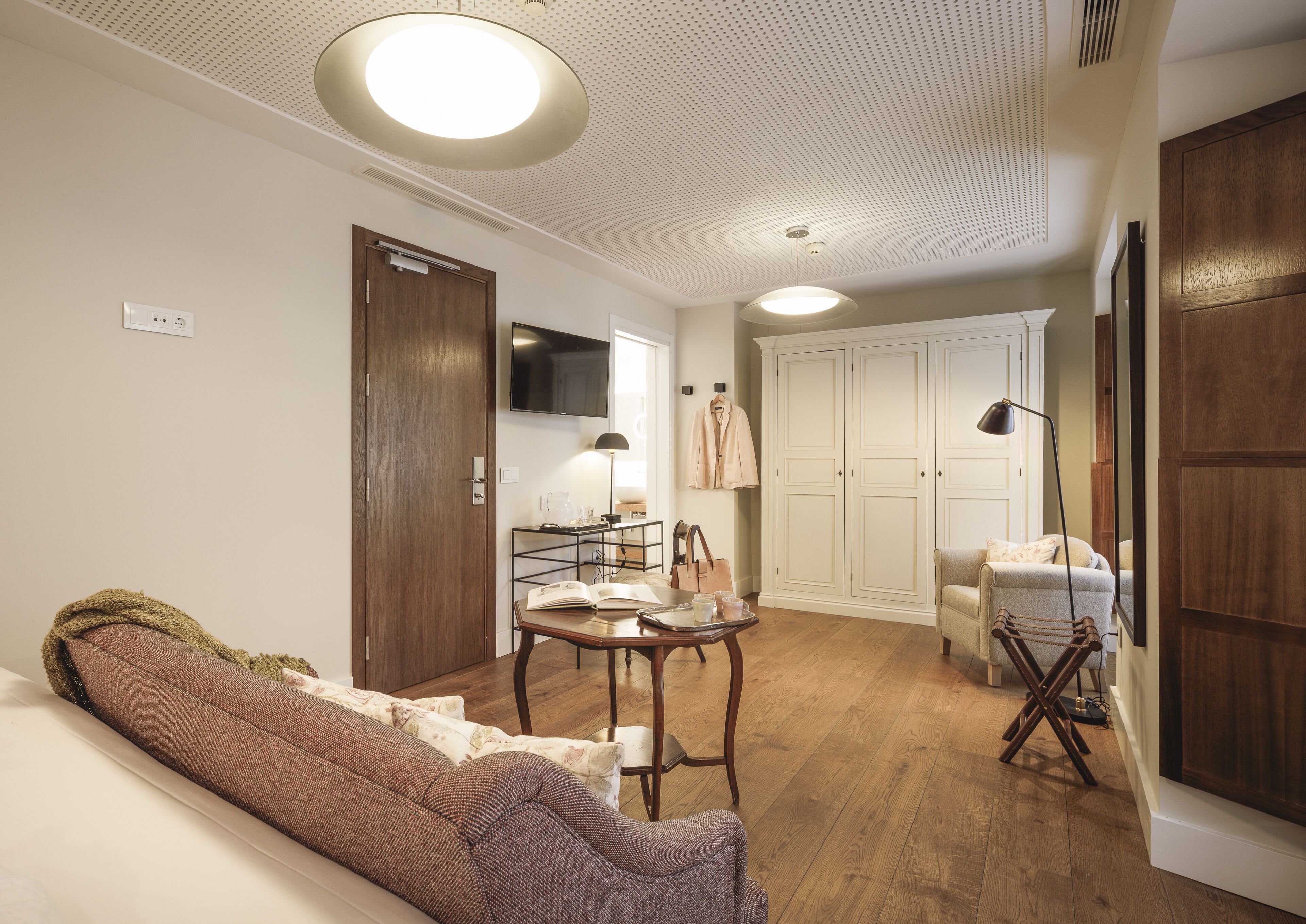 Un salon confortable avec un canapé, une table basse et un téléviseur. On y trouve également une armoire, une lampe et un fauteuil.