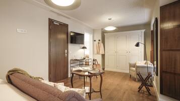 Un salon confortable avec un canapé, une table basse et un téléviseur. On y trouve également une armoire, une lampe et un fauteuil.