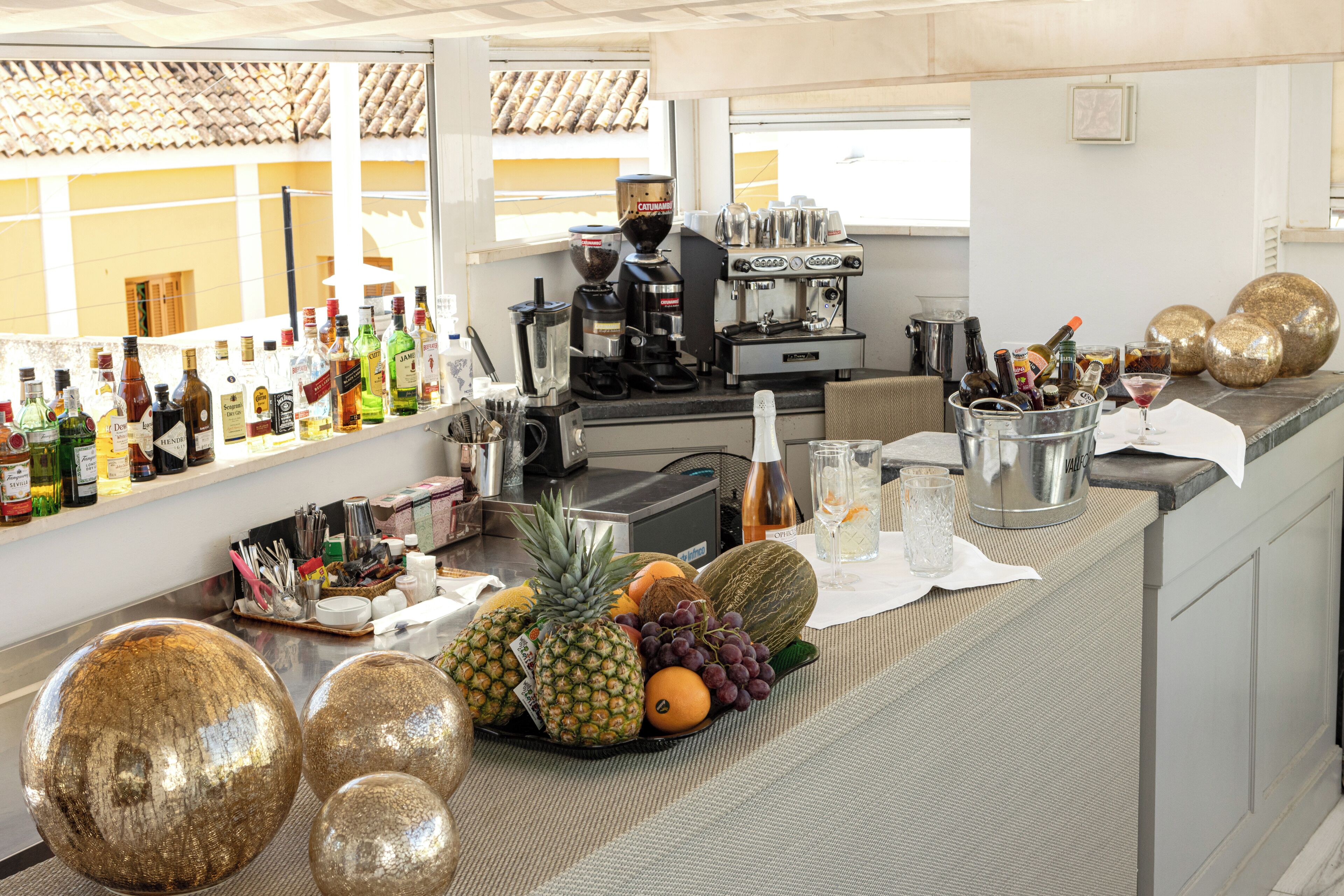 A bar area with a variety of bottles, a coffee machine, and a fruit display.