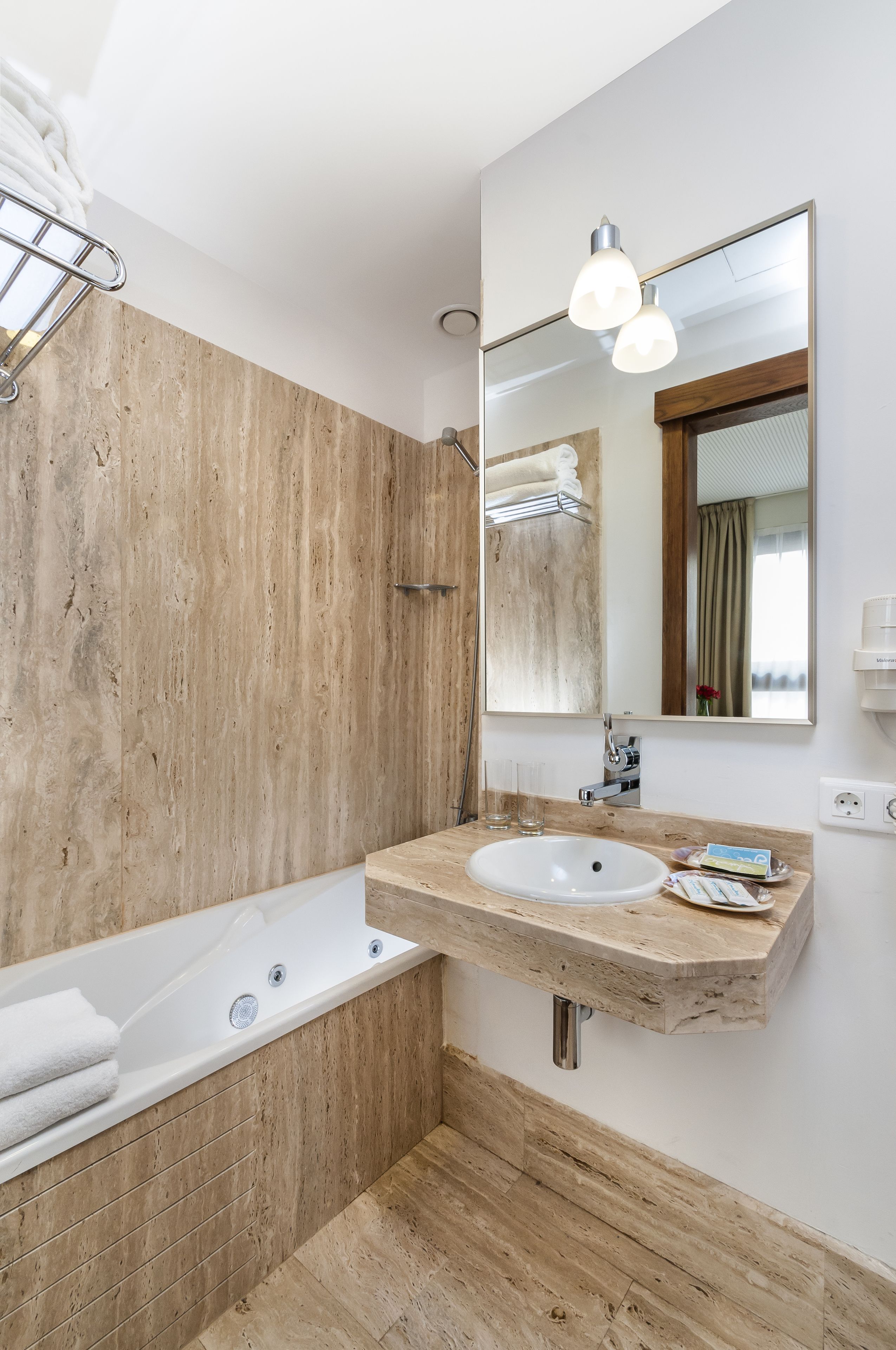 A modern bathroom with a wooden wall, a large mirror, a bathtub, and a sink.