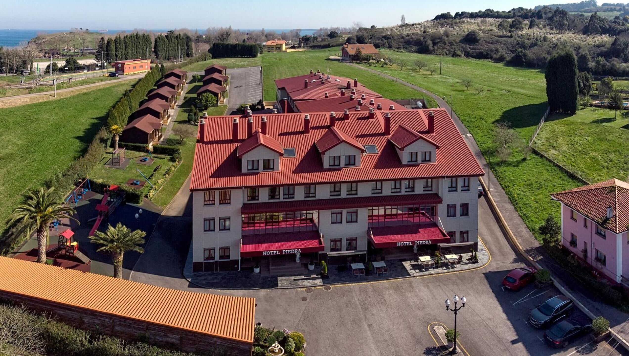 Un hotel con varios edificios de techo rojo, un estacionamiento y un área de juegos.