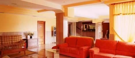 A spacious living room with a red sofa set, a glass coffee table, and a fireplace.