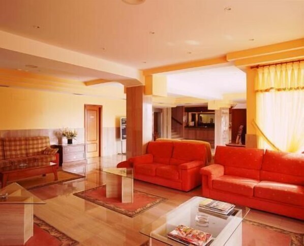 Un salón amplio con un conjunto de sofá rojo, una mesa de centro de vidrio y una chimenea.