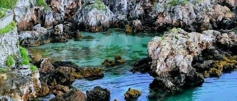 A coastal landscape with rocky terrain and clear water.