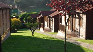 A row of wooden cabins with a stone pathway leading to a grassy area. - Hotel Piedra (Carreno)