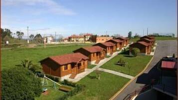 Une rangée de cabanes en bois aux toits rouges, disposées en ligne le long d’une route.