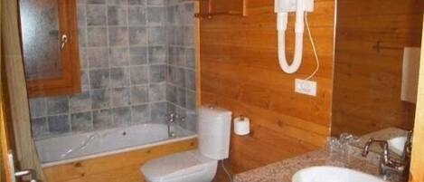 A bathroom with a wooden wall, a bathtub, a toilet, and a sink.