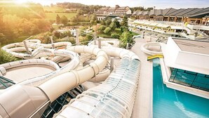 Een modern hotel met een groot zwembad, meerdere glijbanen en een prachtig uitzicht op het omliggende landschap.