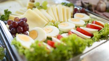 Un buffet proposant une variété d’aliments, notamment du fromage, des raisins, des tomates, de la laitue et des œufs durs.