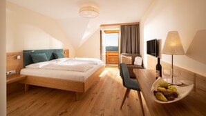 Een hotelkamer met een houten bed, een bureau met een schaal fruit, een lamp en een televisie.