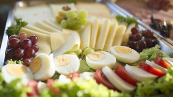 Una bandeja con varios quesos, embutidos, uvas y verduras.