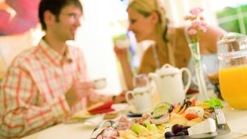 A breakfast setting with a variety of foods on a tray, including fruits, cheeses, and meats.