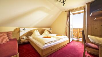 A bedroom with a wooden bed, a red polka dot carpet, a wooden chair, and a balcony with a wooden railing.