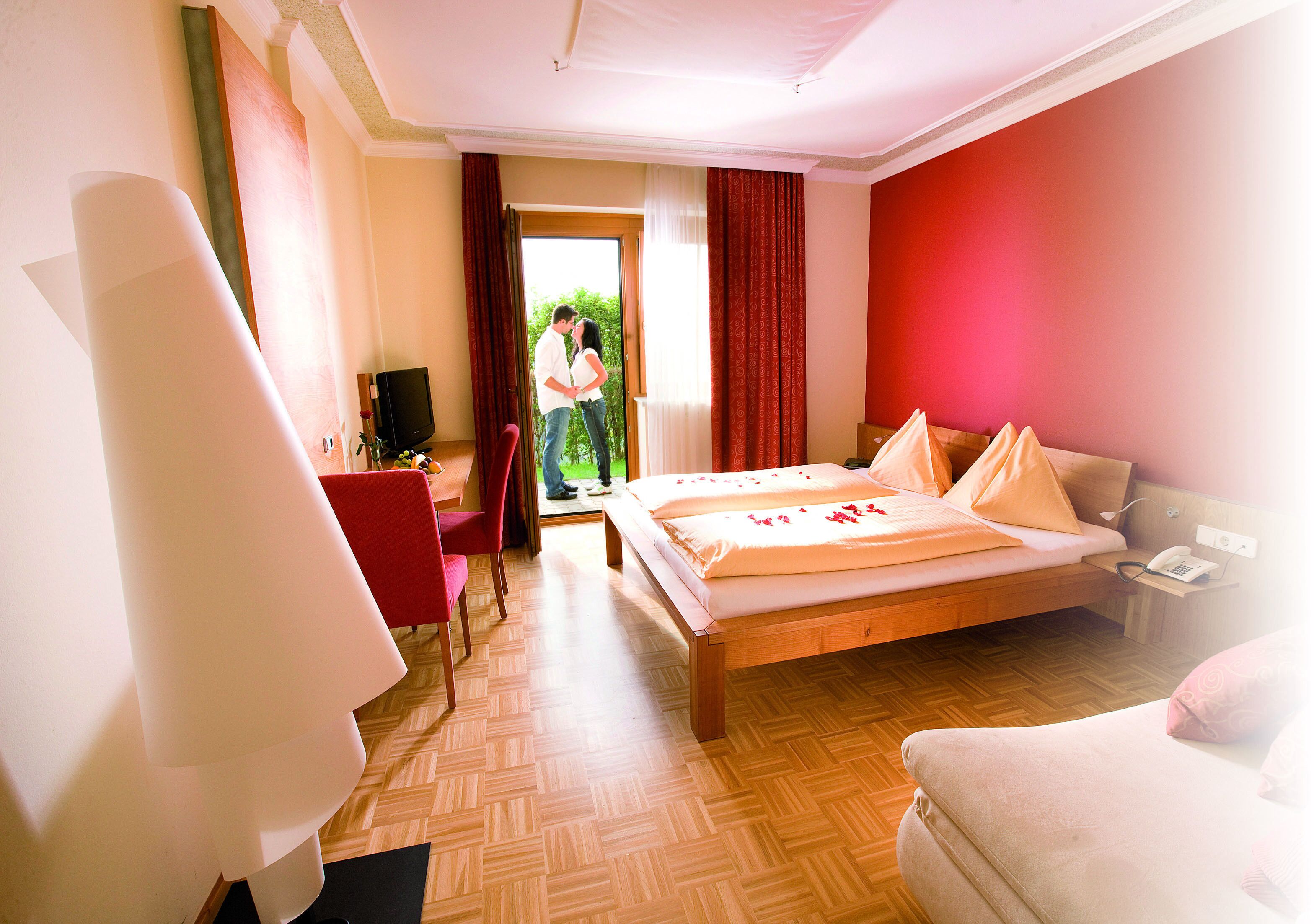 Ein Hotelzimmer mit Bett, Sessel, Schreibtisch und Fernseher.