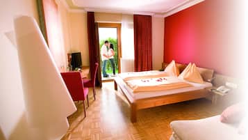 Ein Hotelzimmer mit Bett, Sessel, Schreibtisch und Fernseher.