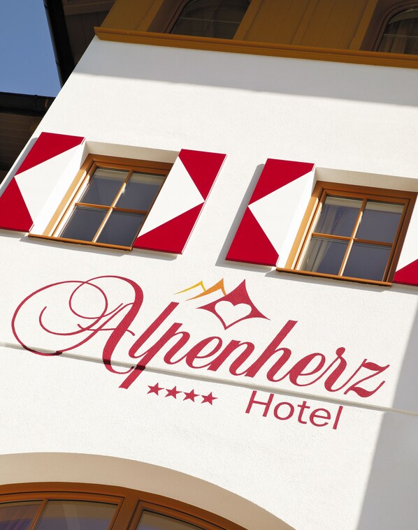 A hotel sign with the name 'Alpenherz Hotel' and decorative elements.