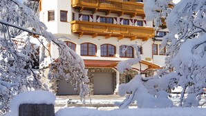 A multi-story hotel with a traditional Alpine architectural style, featuring balconies and a stone facade. - Hotel Alpenherz (Gerlos)