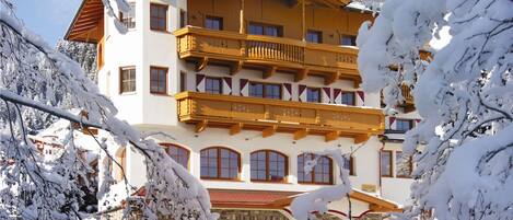 Un hotel de varios pisos con arquitectura alpina tradicional, que cuenta con balcones y fachada de piedra.