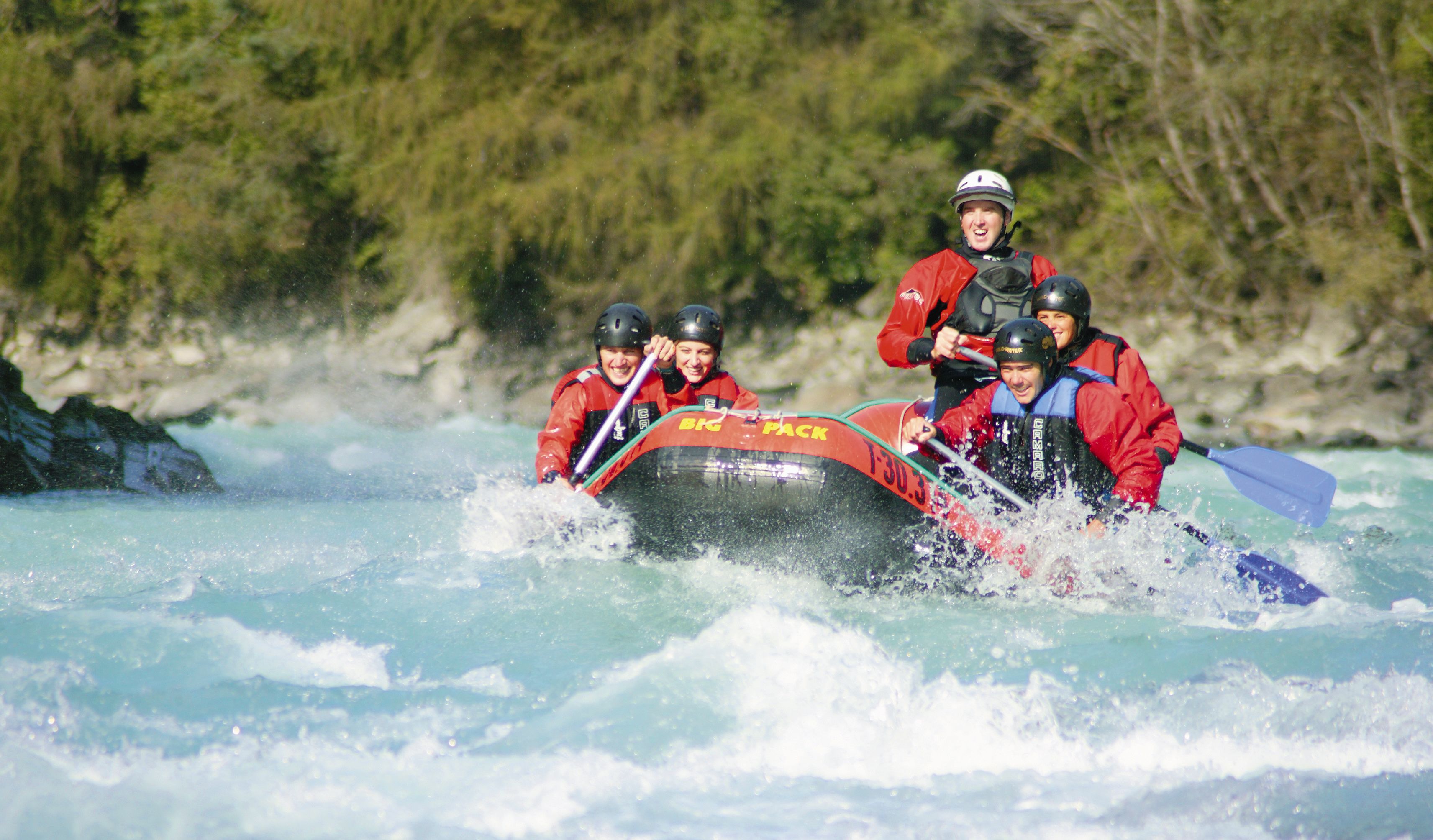 Eine Gruppe von Personen in einem roten Schlauchboot durch einen Fluss.