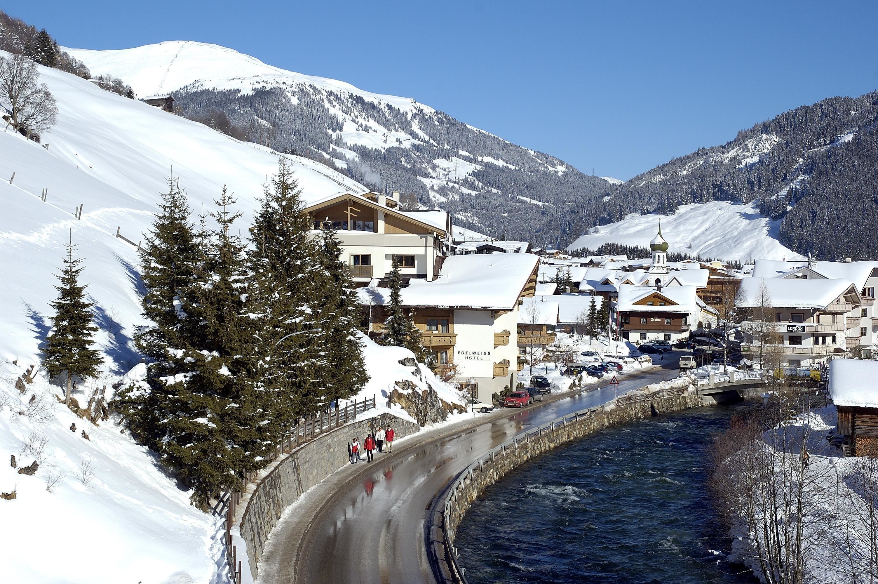 A snow-covered mountain town with a river running through it, featuring a hotel and other buildings.