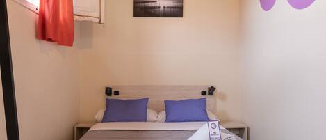 A bedroom with a bed, wooden floor, and a ceiling with exposed beams.