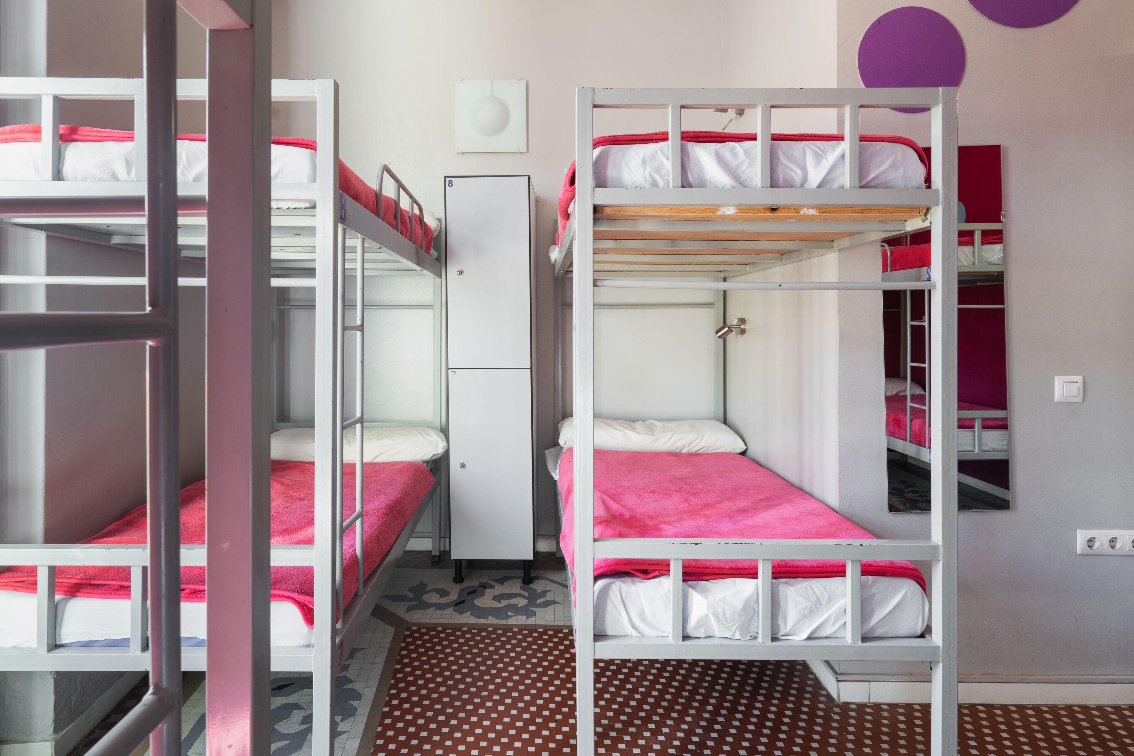 Une chambre de dortoir avec des lits superposés, un réfrigérateur et un tapis à motifs.
