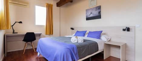 A bedroom with a bed, a desk, a chair, and a window with curtains.