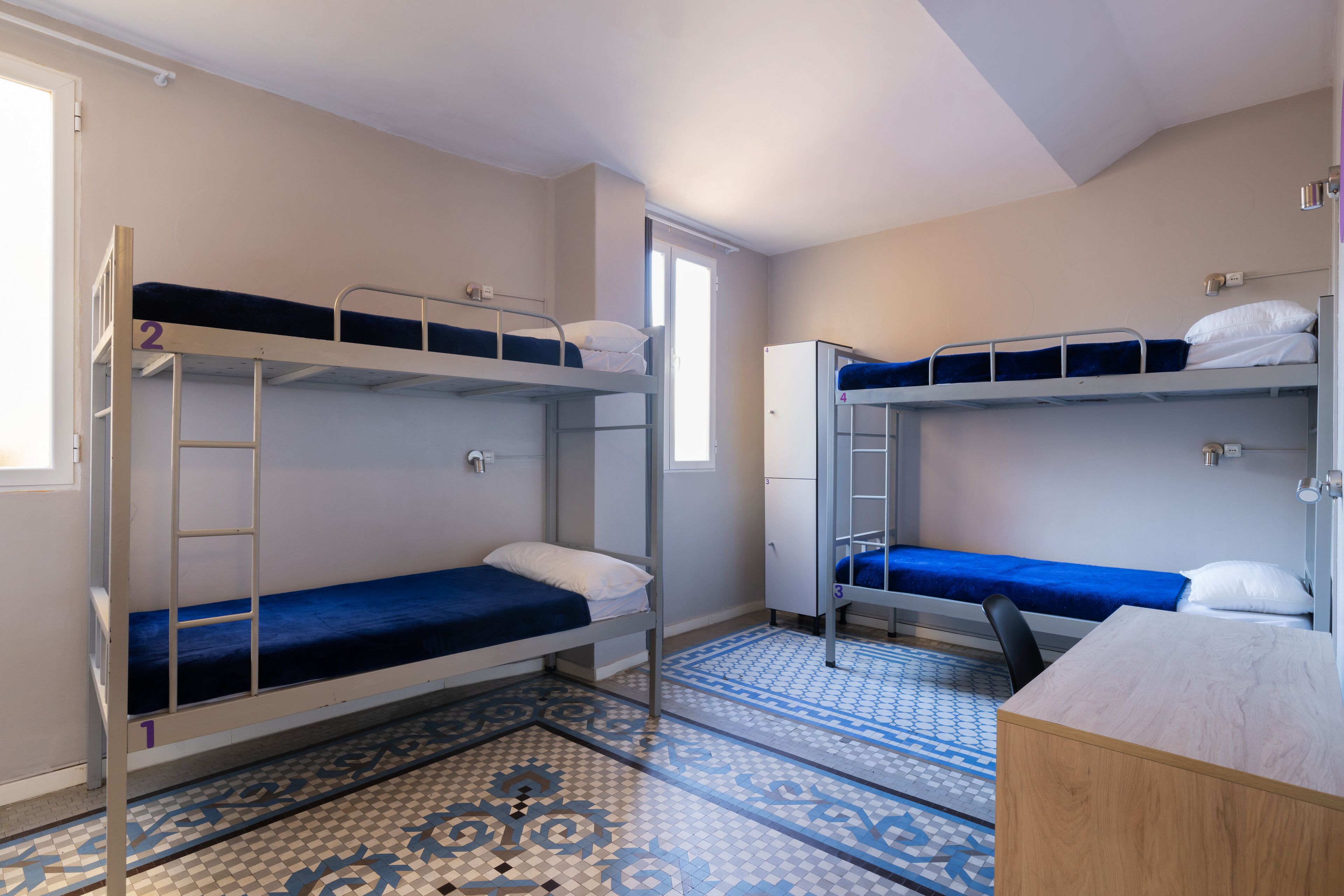 Un dormitorio con literas, un escritorio y un piso con diseño.