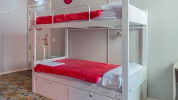 Habitación con literas, suelo estampado, una puerta blanca y una pared con tres círculos rojos.